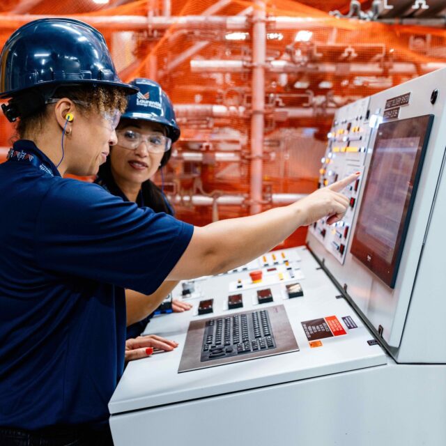 Two workers in front of Laurentis isotope Target Delivery System.